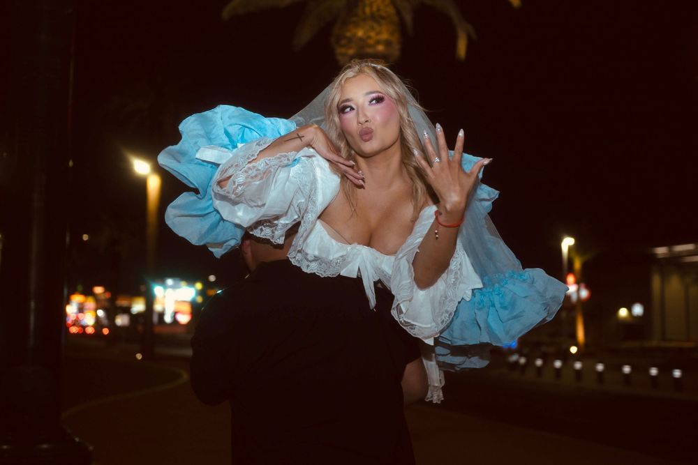 Groom lifting bride in blue ruffled wedding dress on the Las Vegas Strip at night.