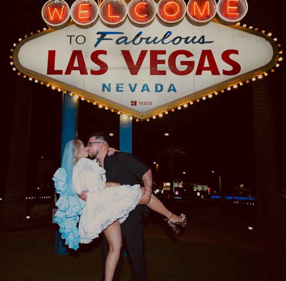 Couple kissing in front of the iconic Welcome to Fabulous Las Vegas Nevada sign at night.