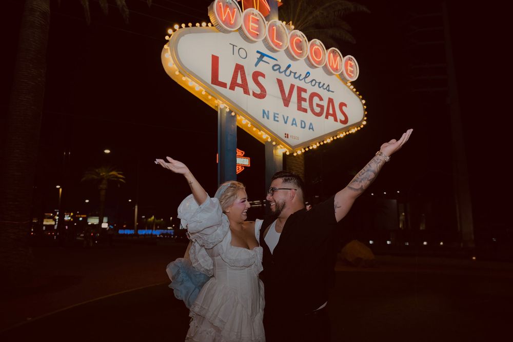 Couple celebrating in front of the iconic Welcome to Fabulous Las Vegas Nevada sign at night.