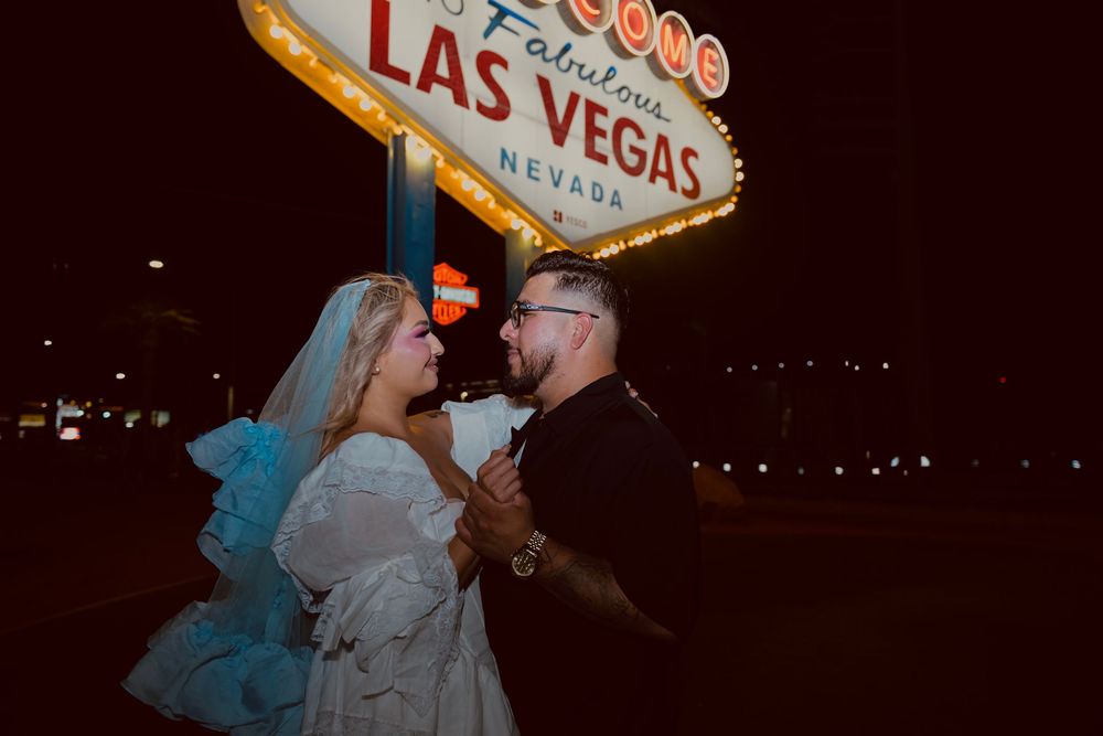 Couple in wedding attire posing at night in front of the iconic Welcome to Fabulous Las Vegas Nevada sign.