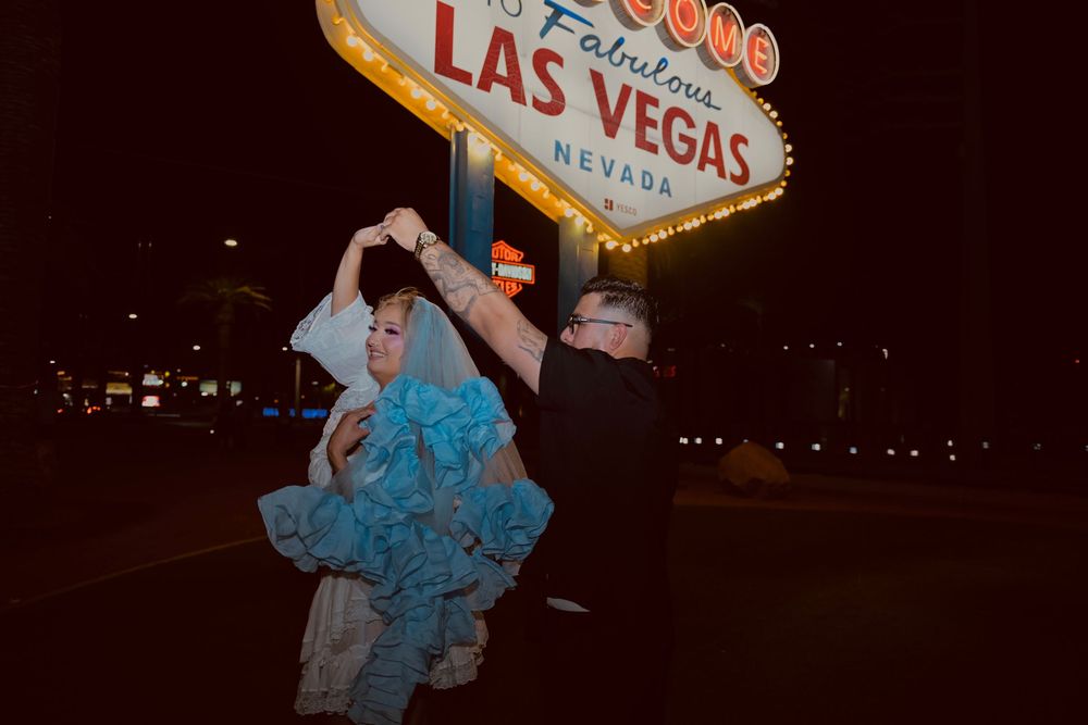 Couple dancing in front of the iconic Welcome to Fabulous Las Vegas Nevada sign at night.