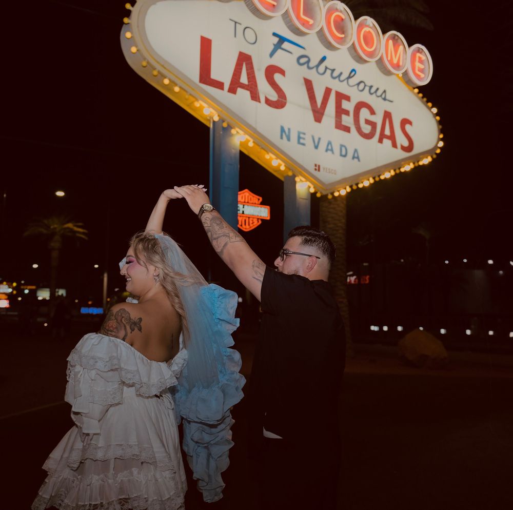 Couple dancing in wedding attire at night in front of the Welcome to Fabulous Las Vegas Nevada sign.