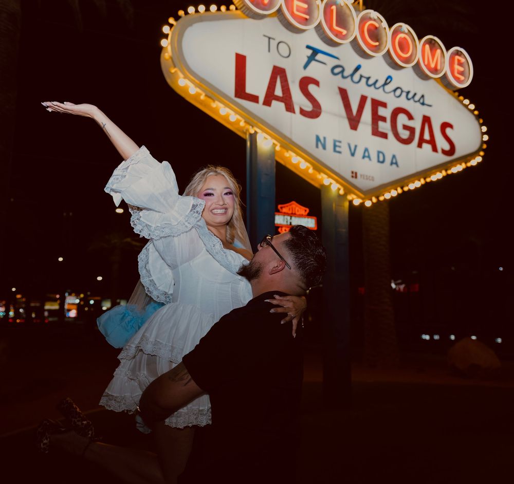 Couple celebrating a Las Vegas wedding at the iconic Welcome to Fabulous Las Vegas sign at night.