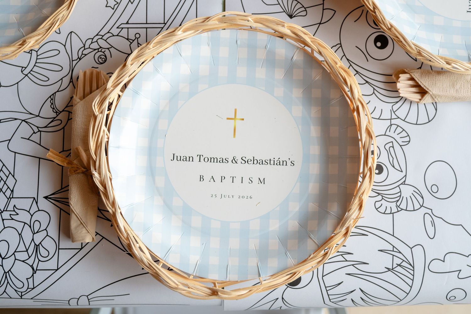 Blue gingham baptism plate personalized for Juan Tomas and Sebastian's baptism with gold cross, displayed in wicker basket.