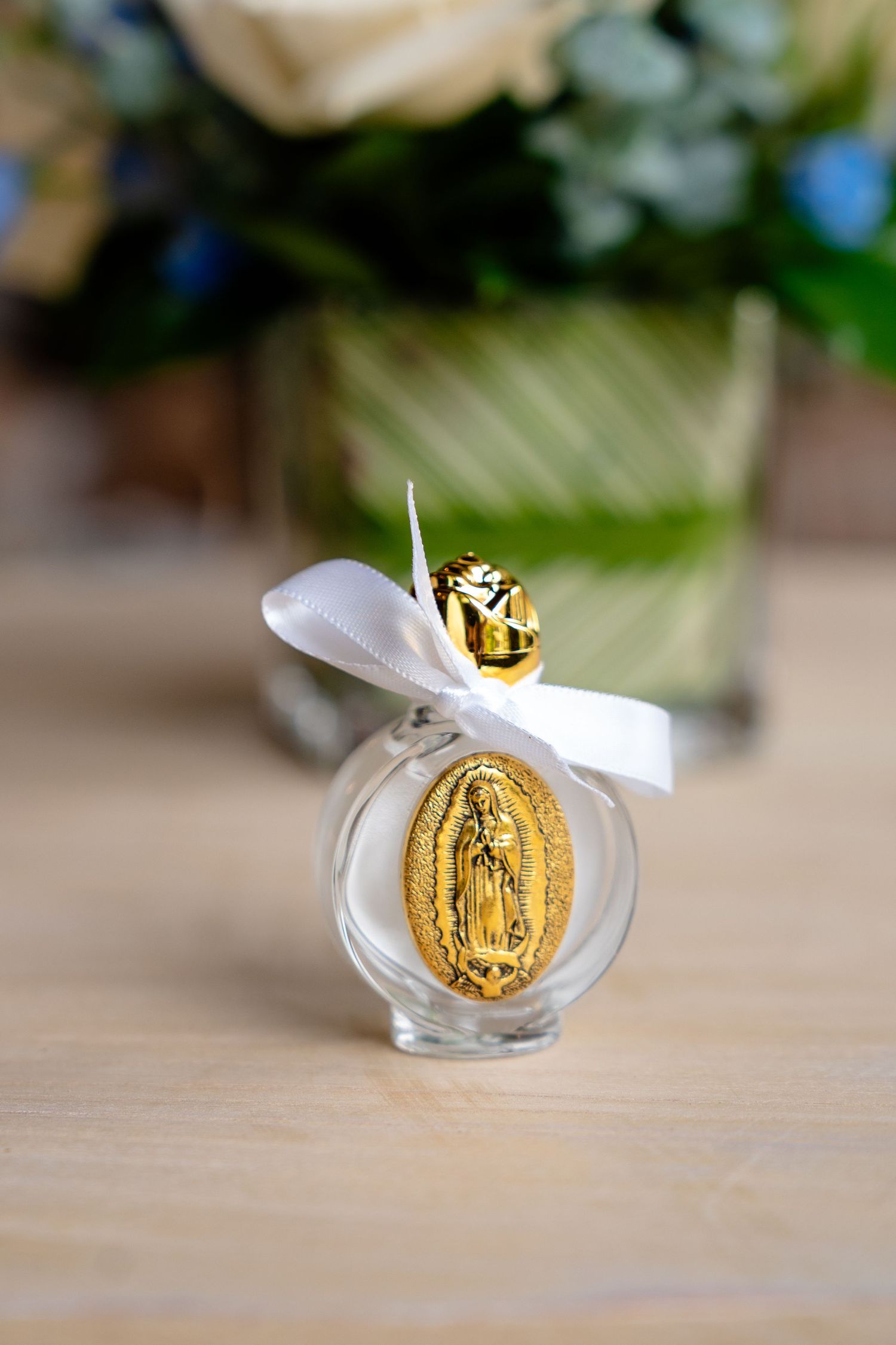 Gold Virgin Mary medallion glass favor bottle with white bow, ideal for religious events.