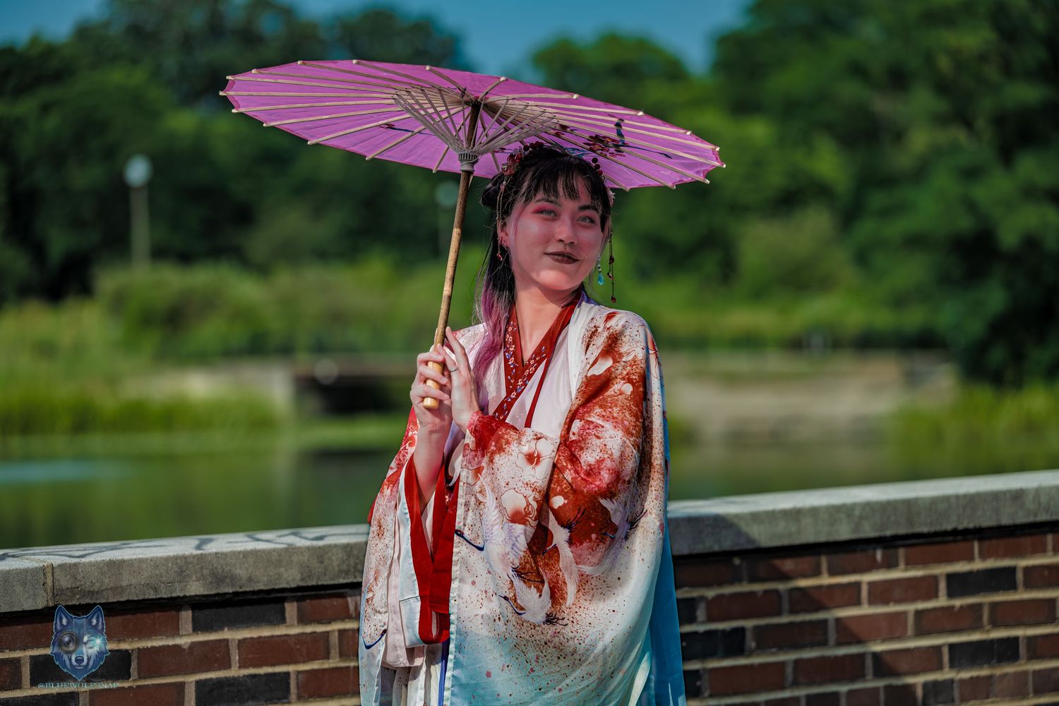 Woman in traditional Chinese Hanfu costume with blood effects holds pink parasol near lake. Chi.Shooters meet yutonew