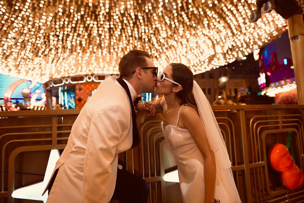 Newlywed couple sharing a kiss under sparkling lights in a glamorous Las Vegas wedding venue.