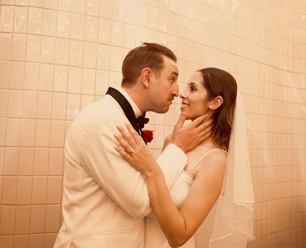 Groom in white tuxedo tenderly holds bride's face for a kiss on their Las Vegas wedding day.