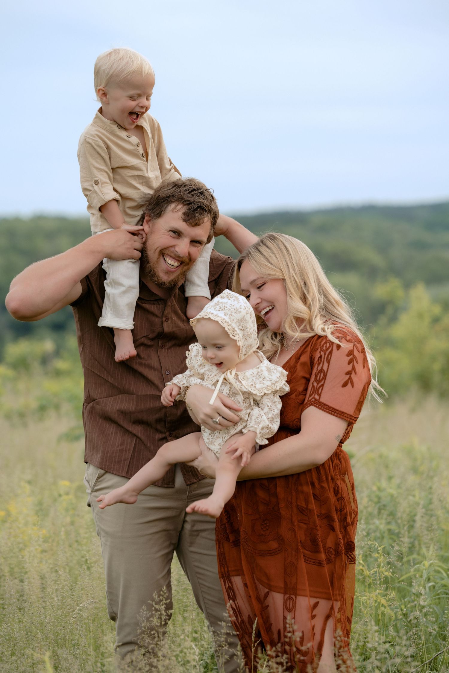 Young parents tickle their kids during a candid outdoor summer family session in Hudson, WI.