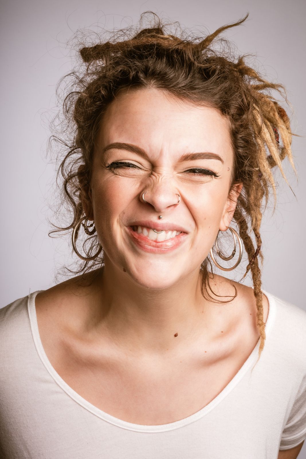 Expressief portret van een lachende vrouw met dreadlocks en gezichtspiercings in de studio van Bart Boodts Photography in Hemiksem.