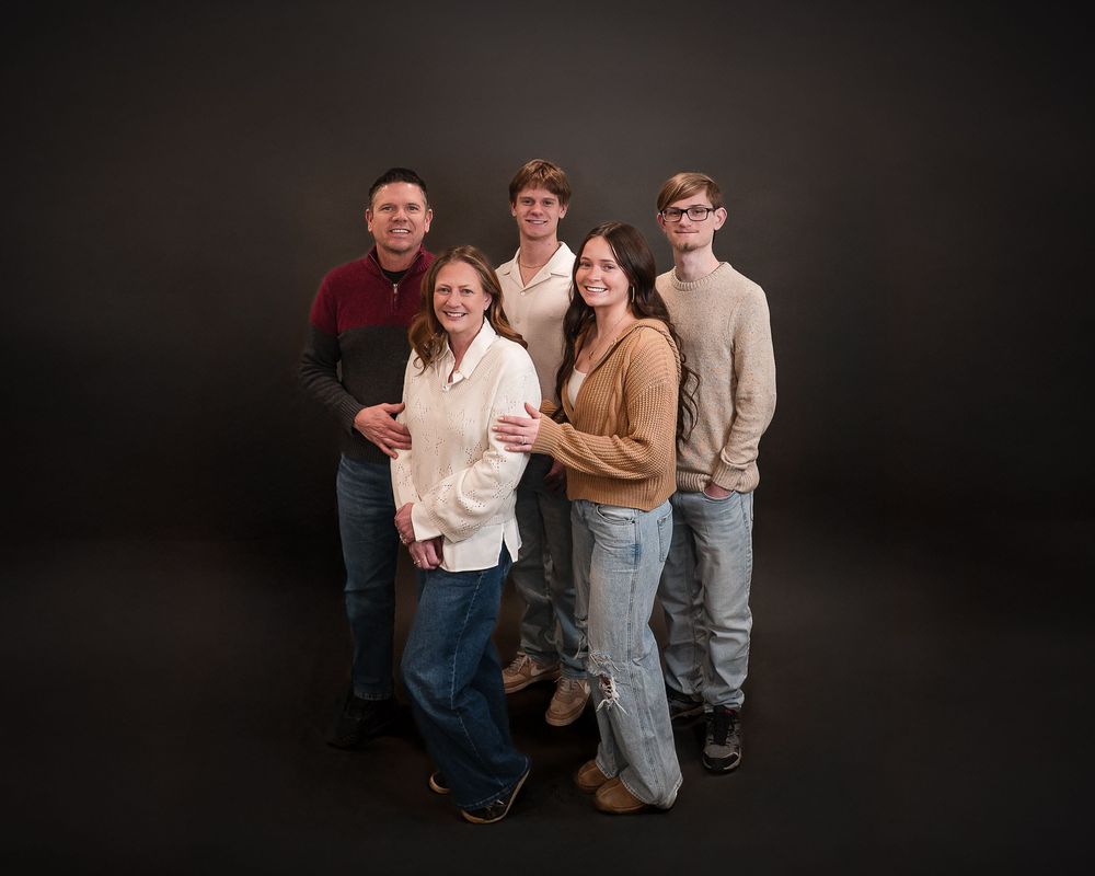 Family of six posing together for a professional portrait against a dark studio background.