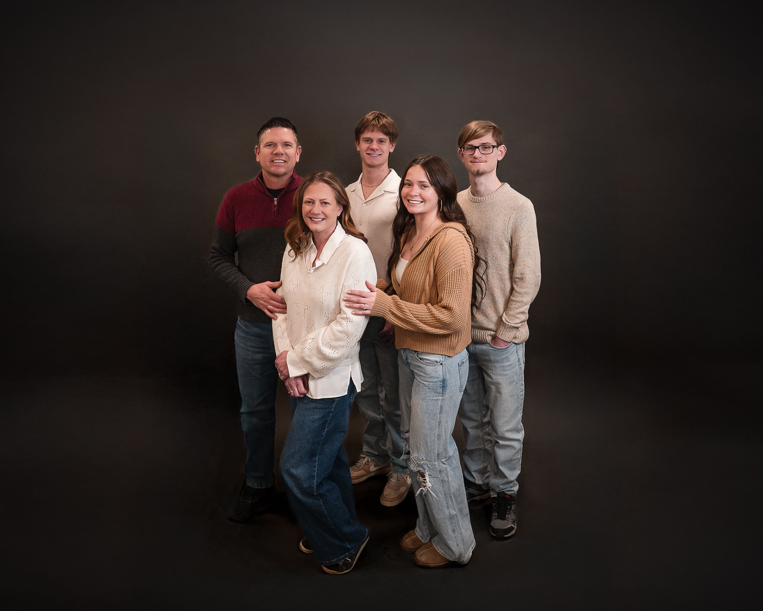 Family of six posing together for a professional portrait against a dark studio background.