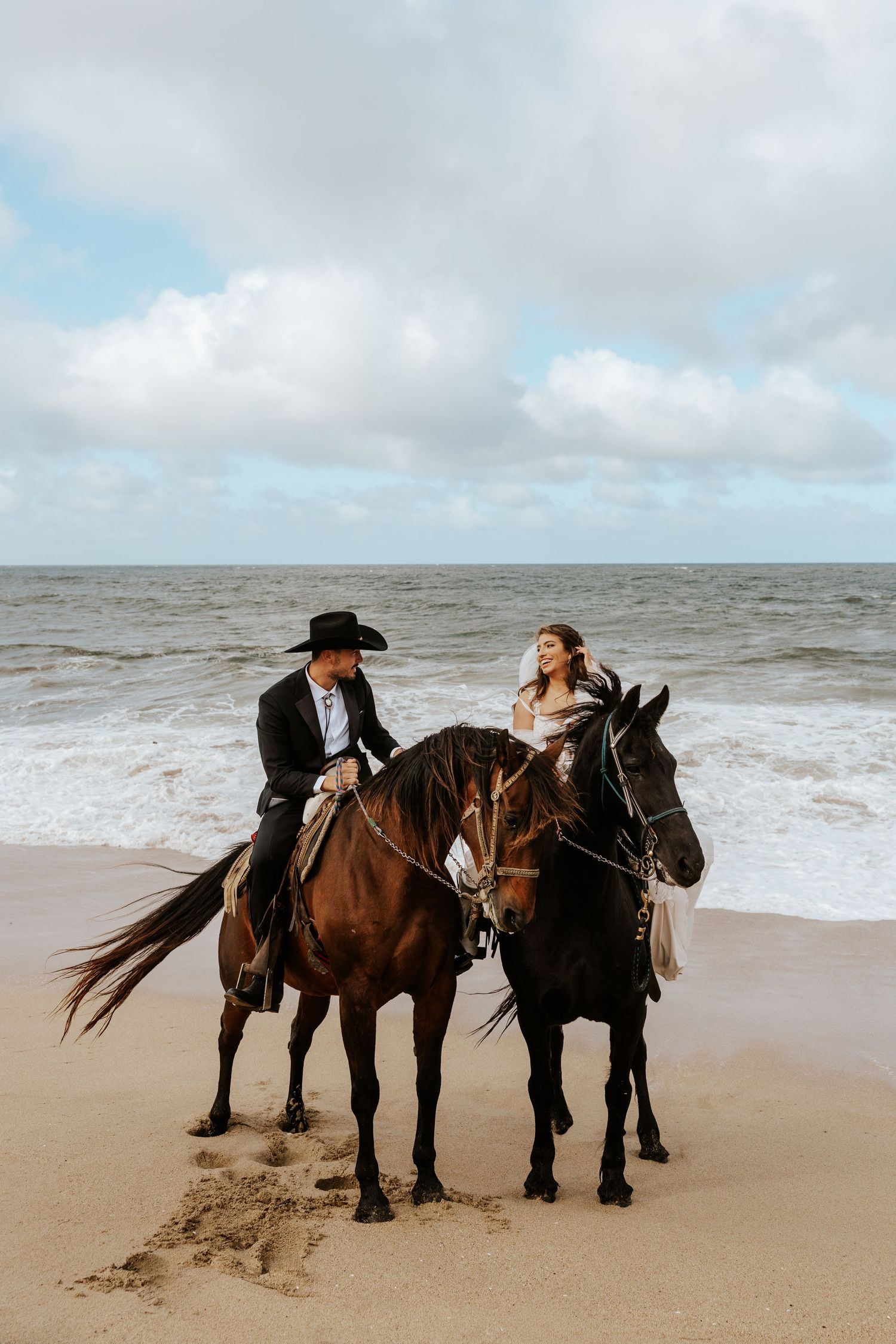 playful couple riding horses on beach in Half Moon Bay during Bay Area elopement