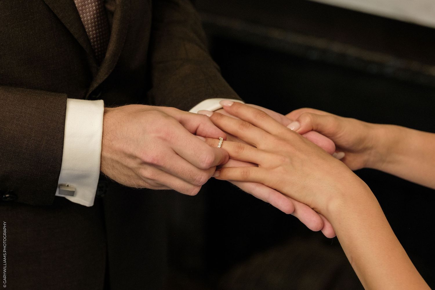 Groom placing a wedding ring on bride's finger during a wedding ceremony.