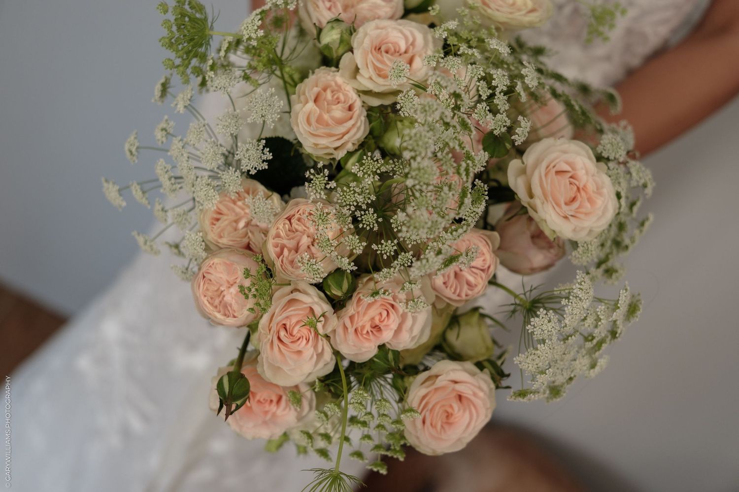 Bride holding a romantic wedding bouquet of soft pink roses and white baby's breath flowers.