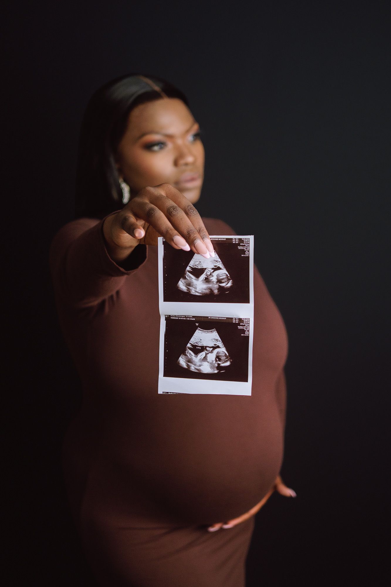 Expecting mother holding ultrasound scan photo of baby Amila during maternity portrait session