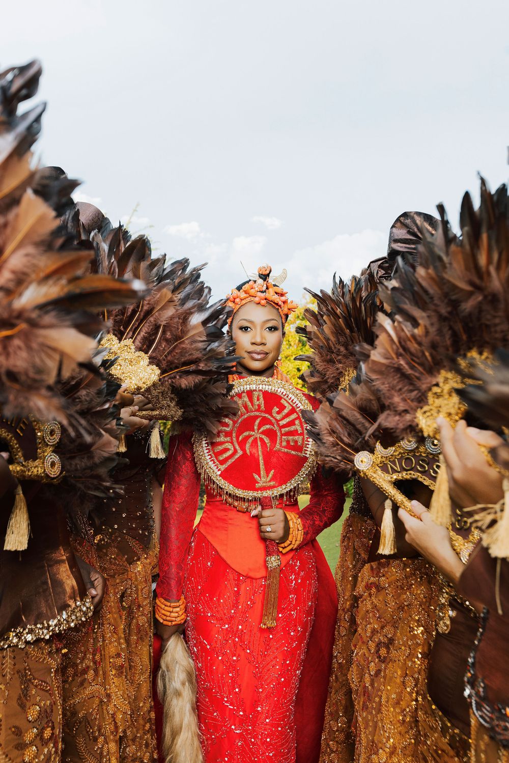 Woman in red traditional costume with large brown feather wings at a cultural carnival festival.