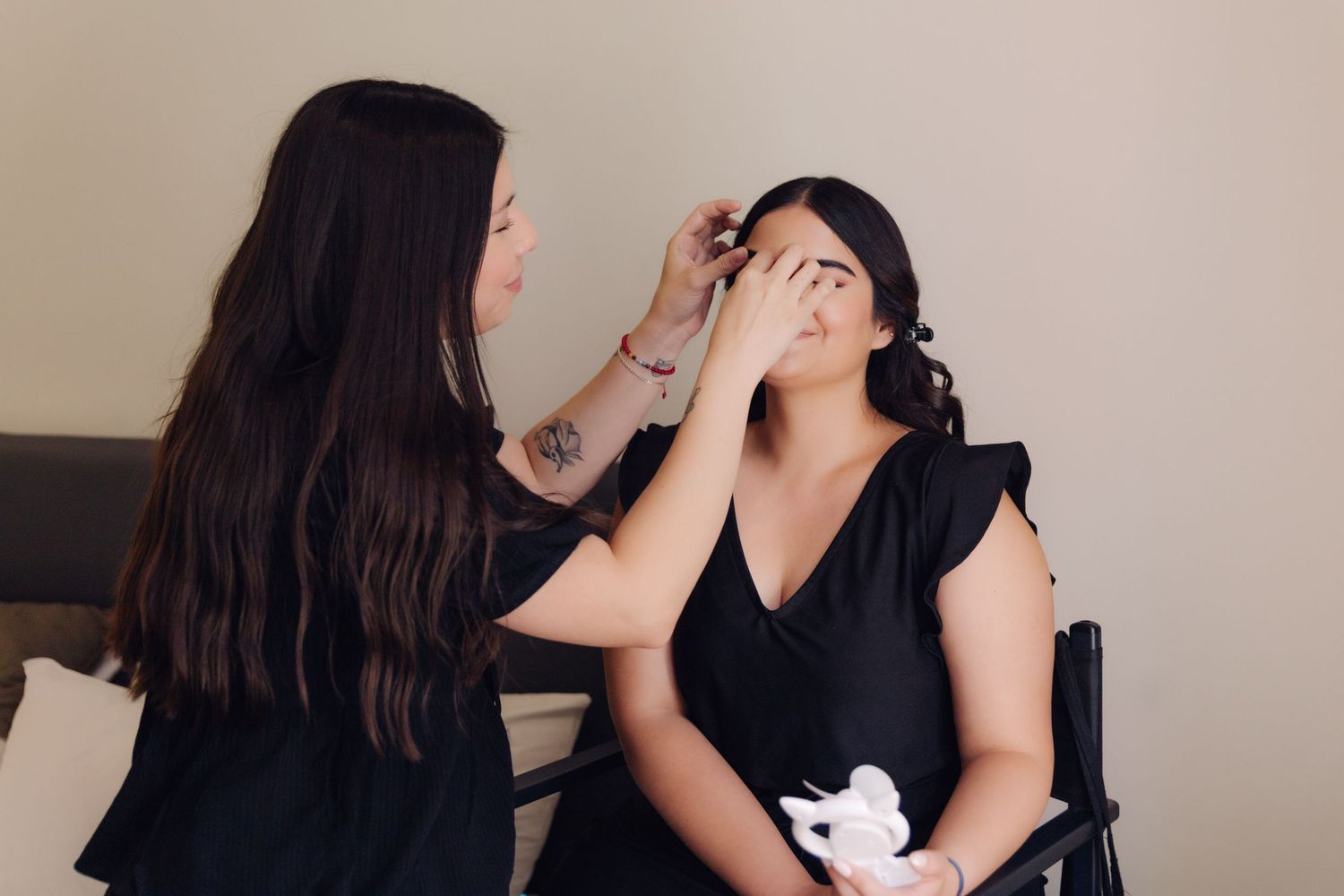 Professional makeup artist applying eye makeup to a seated bride during wedding day preparations.