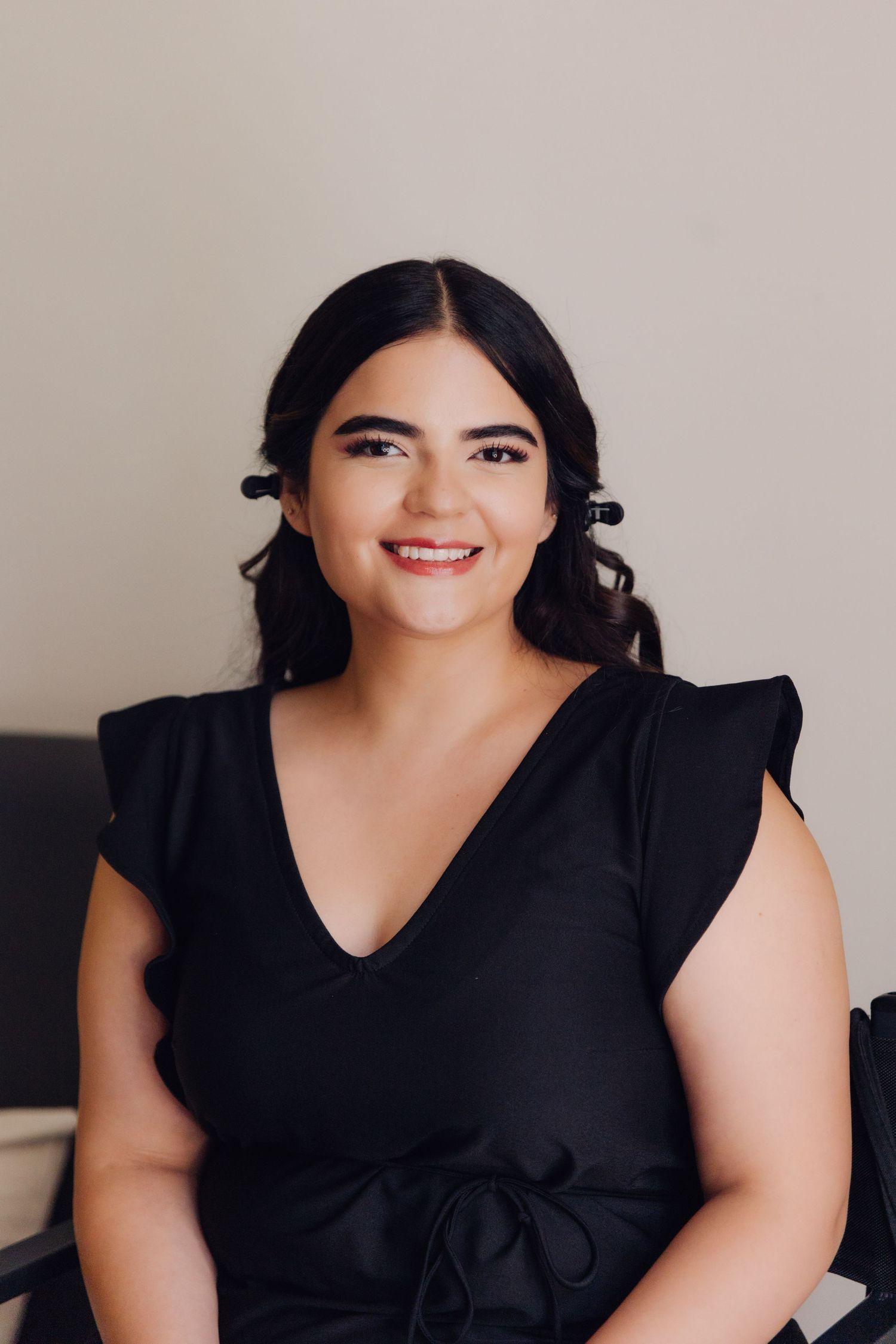 Beautiful brunette bride-to-be smiling in black ruffled dress during wedding day preparation.