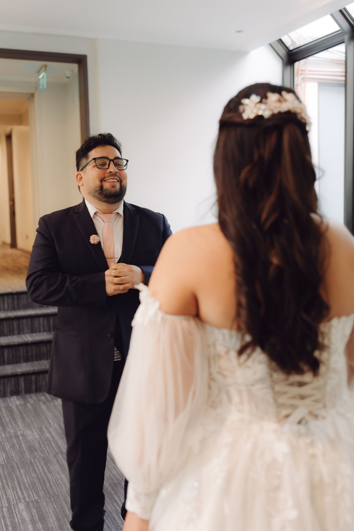 Emotional groom reacts seeing bride in white tulle wedding gown during first look reveal.