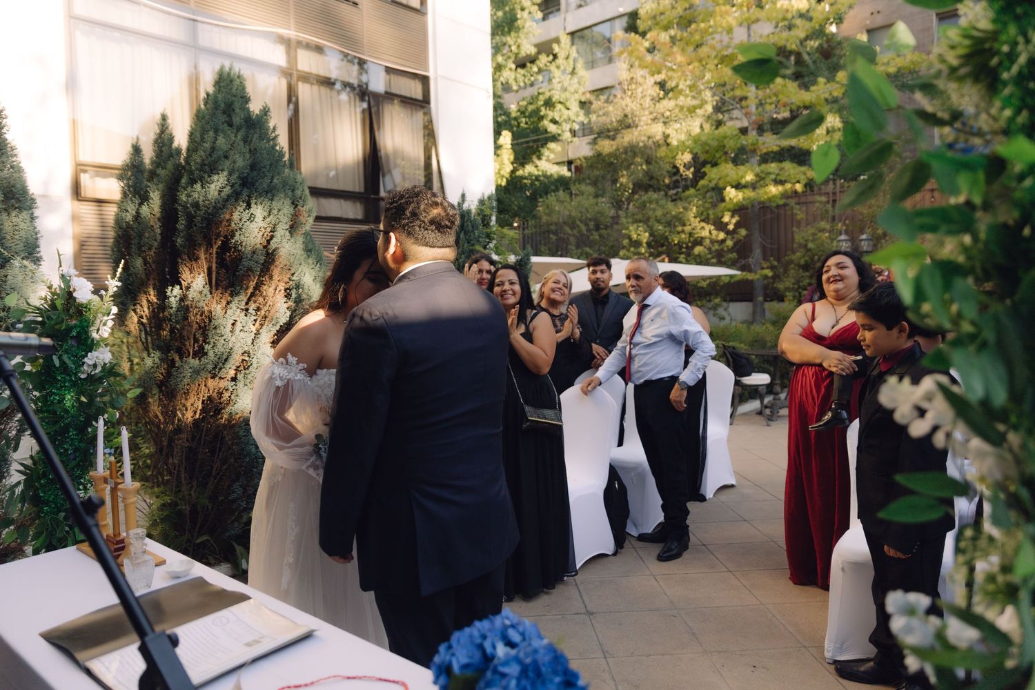 Bride and groom share emotional first meeting at outdoor wedding ceremony with cheering guests.