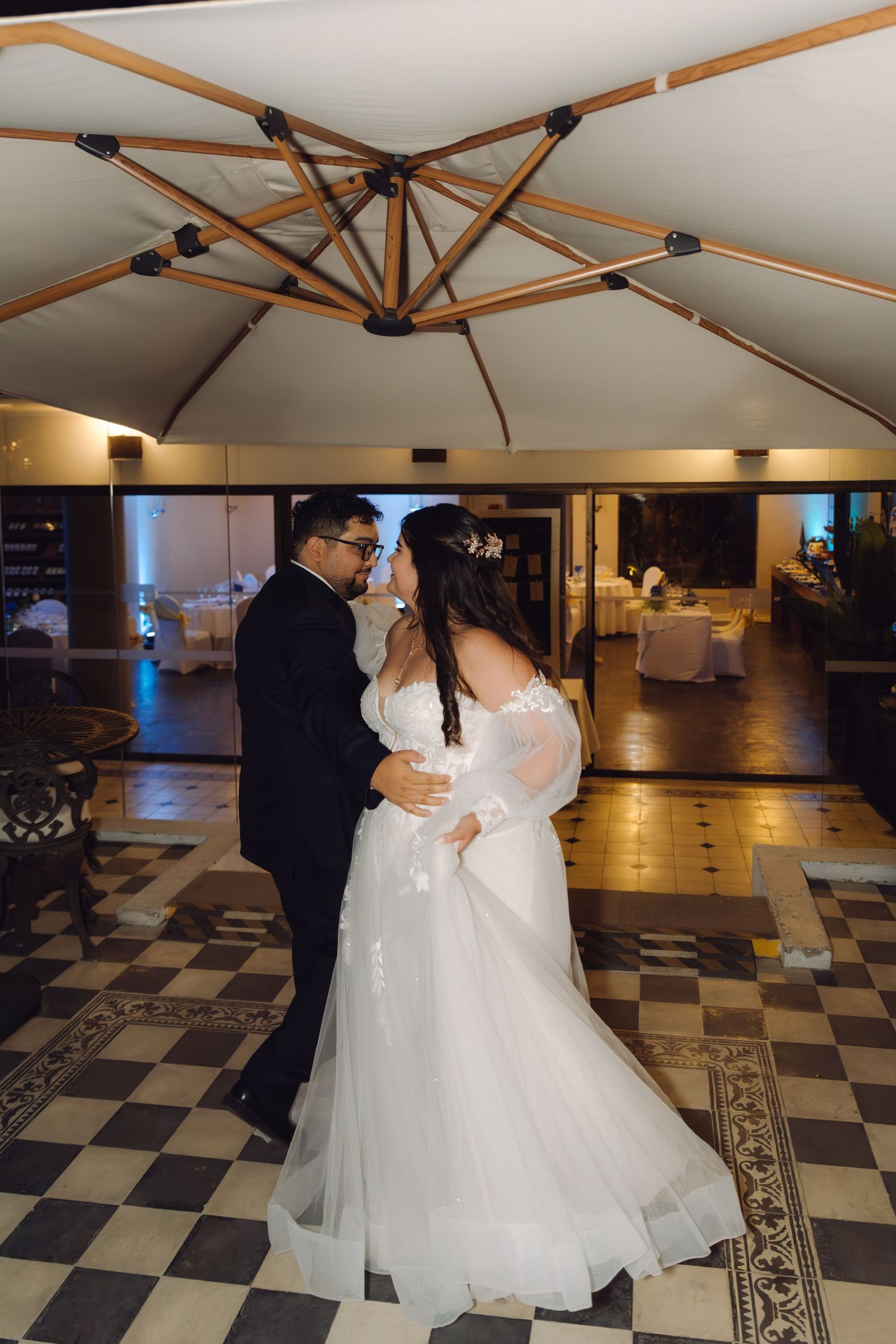 Bride and groom sharing a romantic moment during first dance on classic black and white checkered floor.