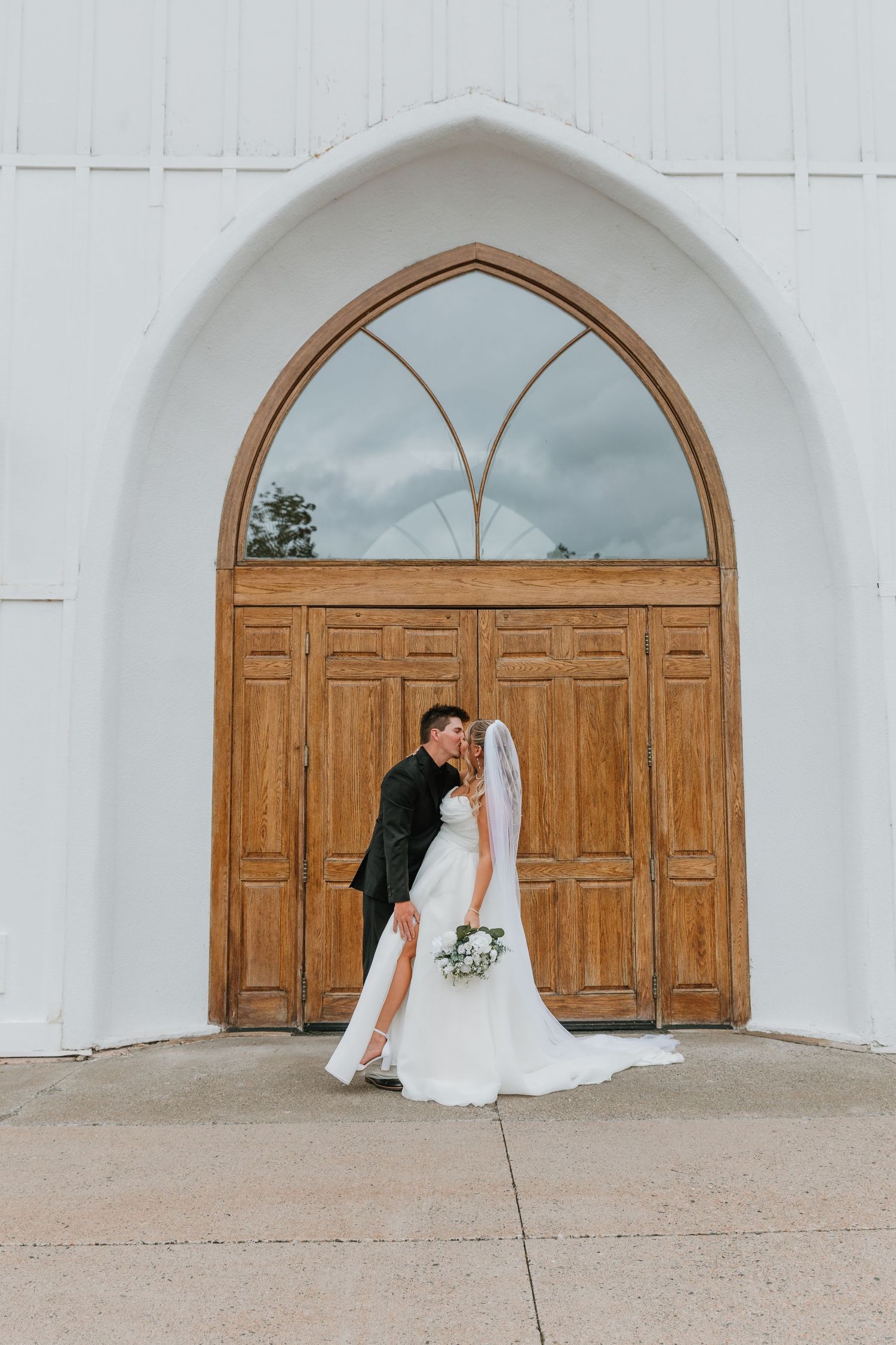 Couple kissing outside of our lady of perpetual peace church in Rothesay NB