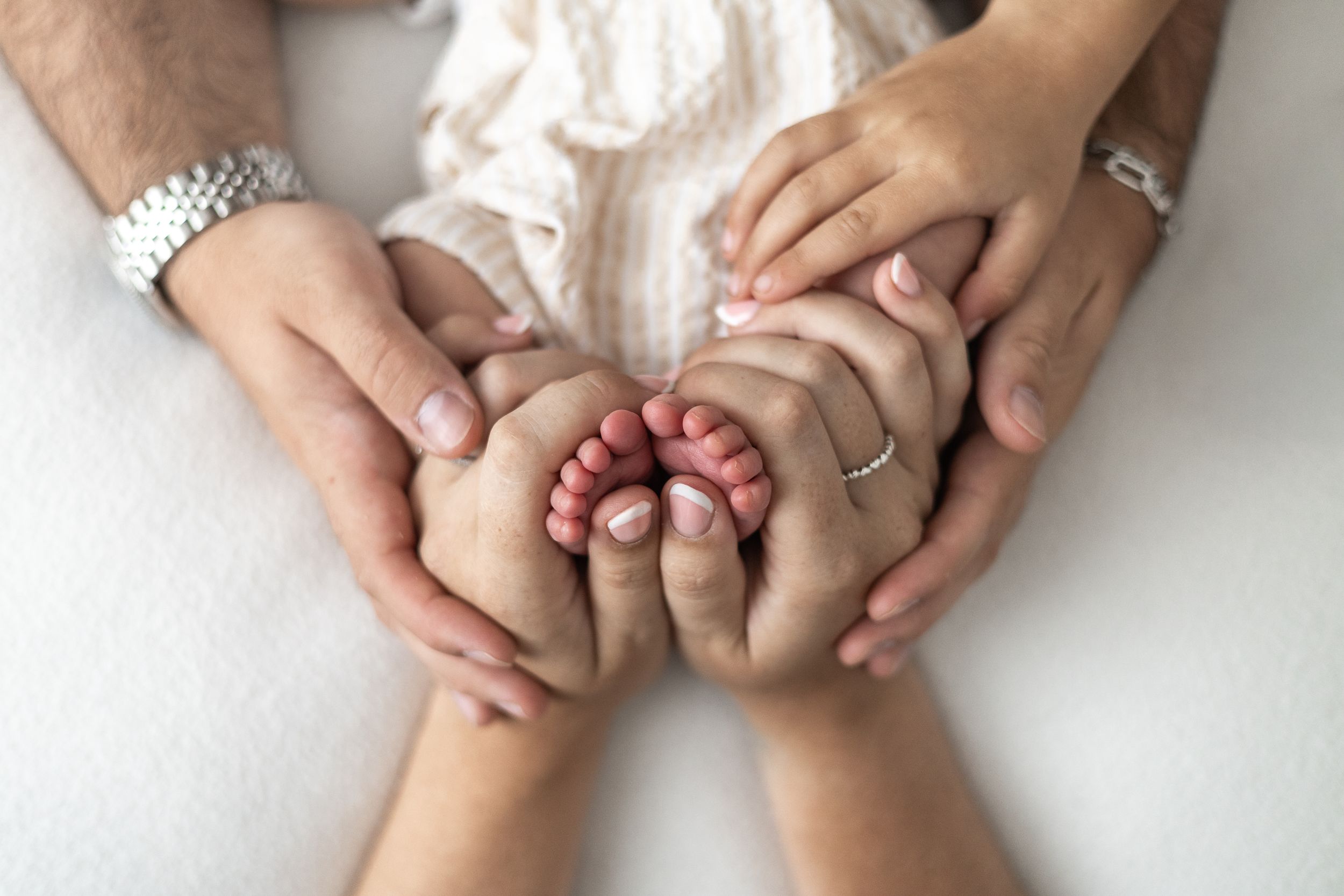 Parents hands cradling tiny newborn baby toes, a tender family moment capturing new parenthood natural baby photography Nottingham