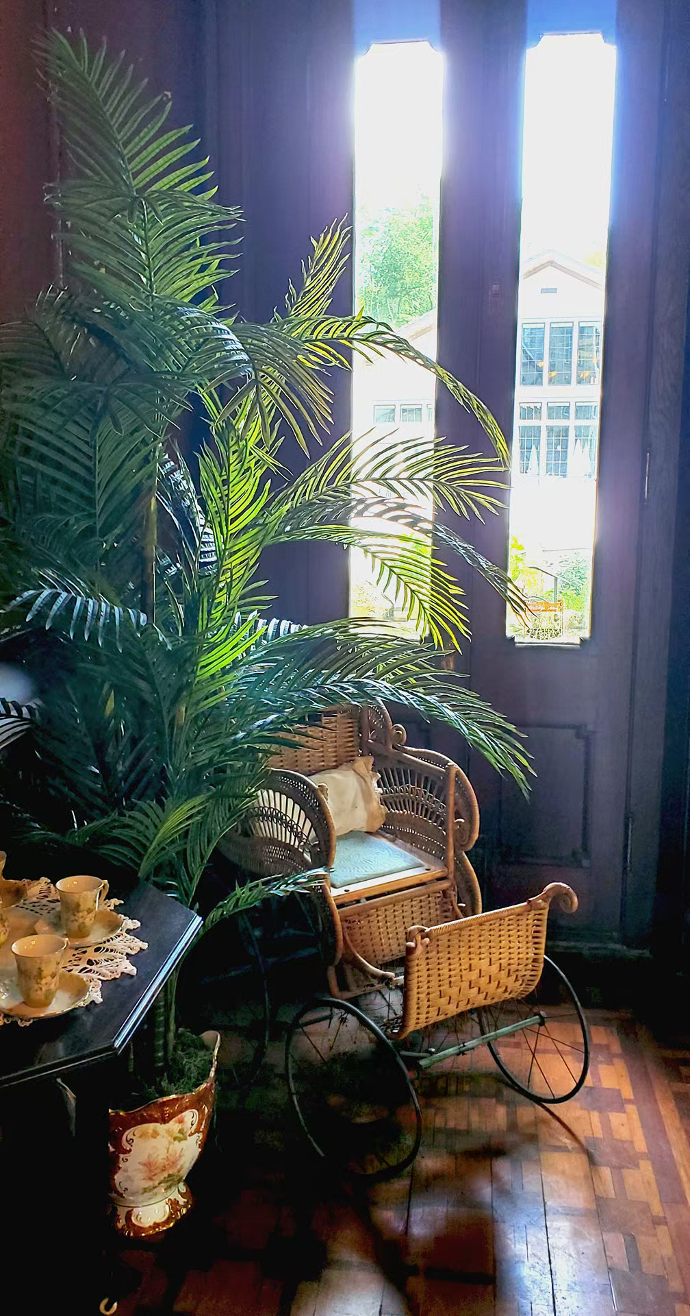 Vintage wicker baby carriage beside a lush palm plant in the mac-o-chee wedding venue castle