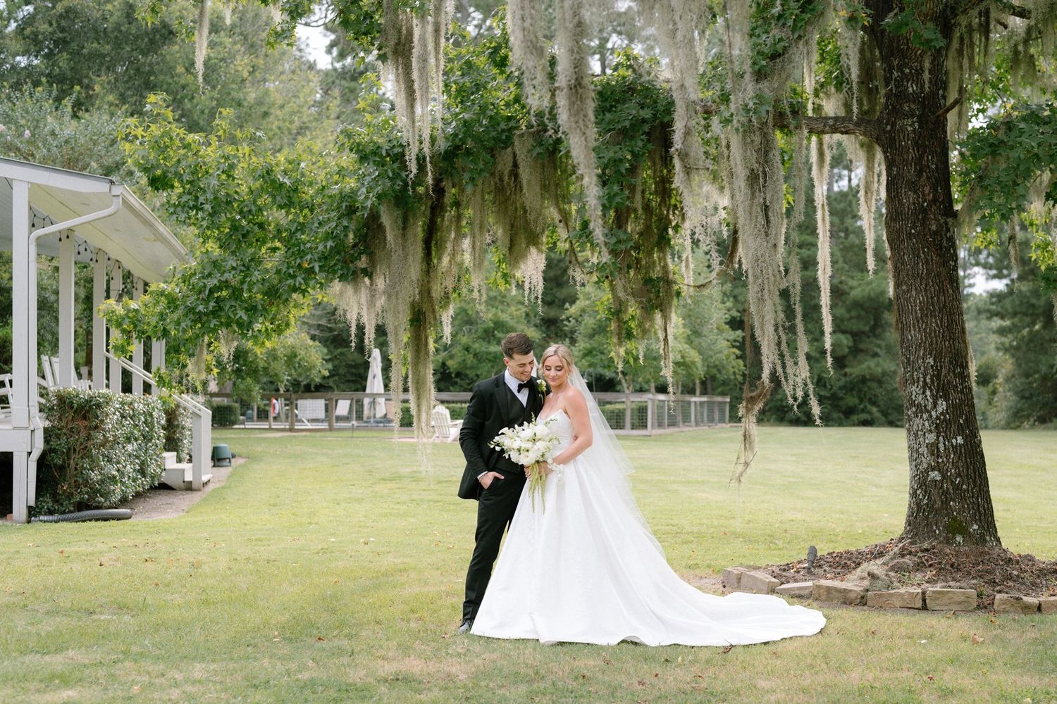 Bride and groom posing under a mossy oak tree at Historic Hill House in Willis Texas.