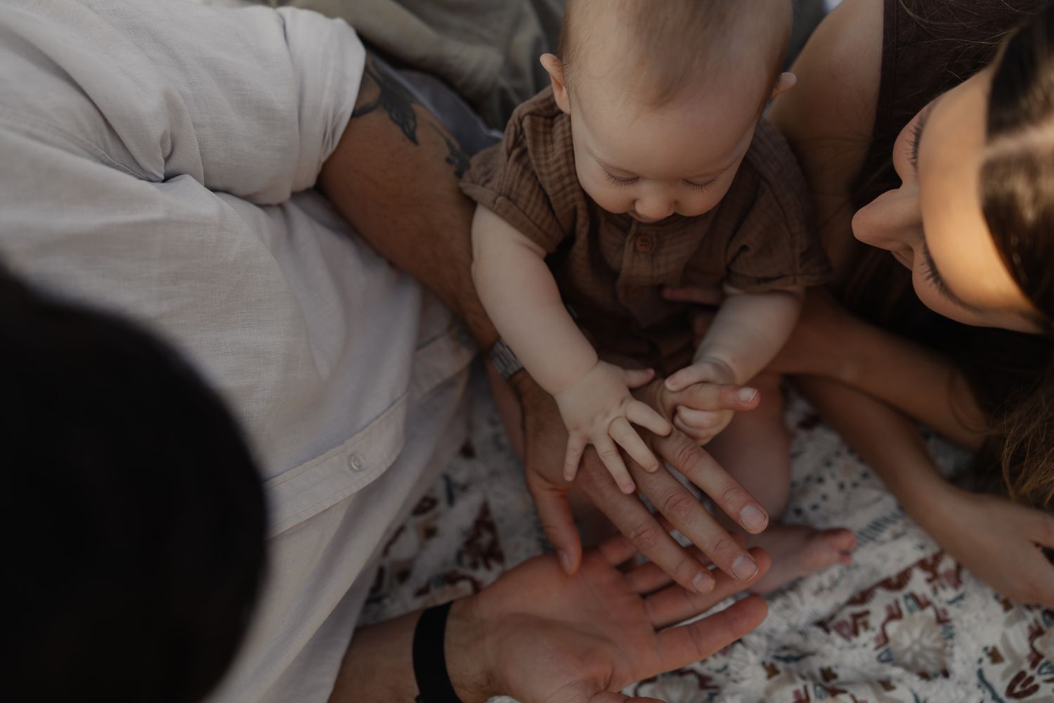 Baby reaches for their parents’ hands during a relaxed lifestyle in-home family photoshoot.