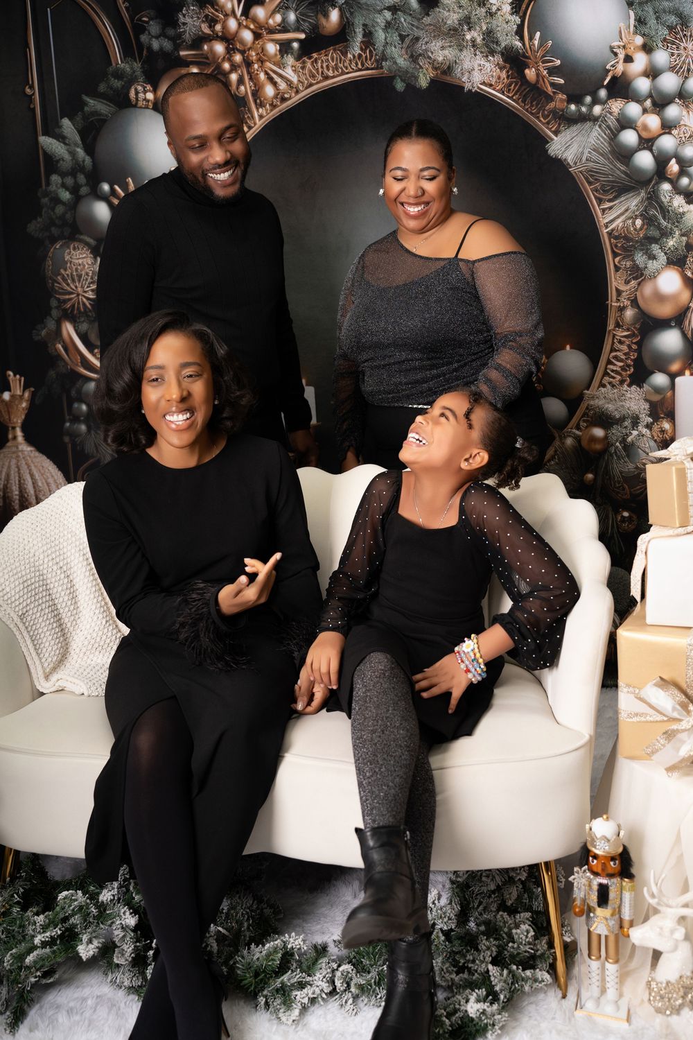 Joyful family of four in matching black outfits posing with Christmas decorations.