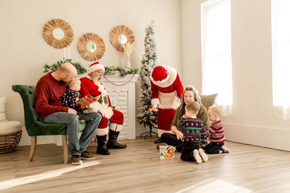 Two families with children enjoy a festive Santa Claus photo session in a bright, decorated living room at Christmas.