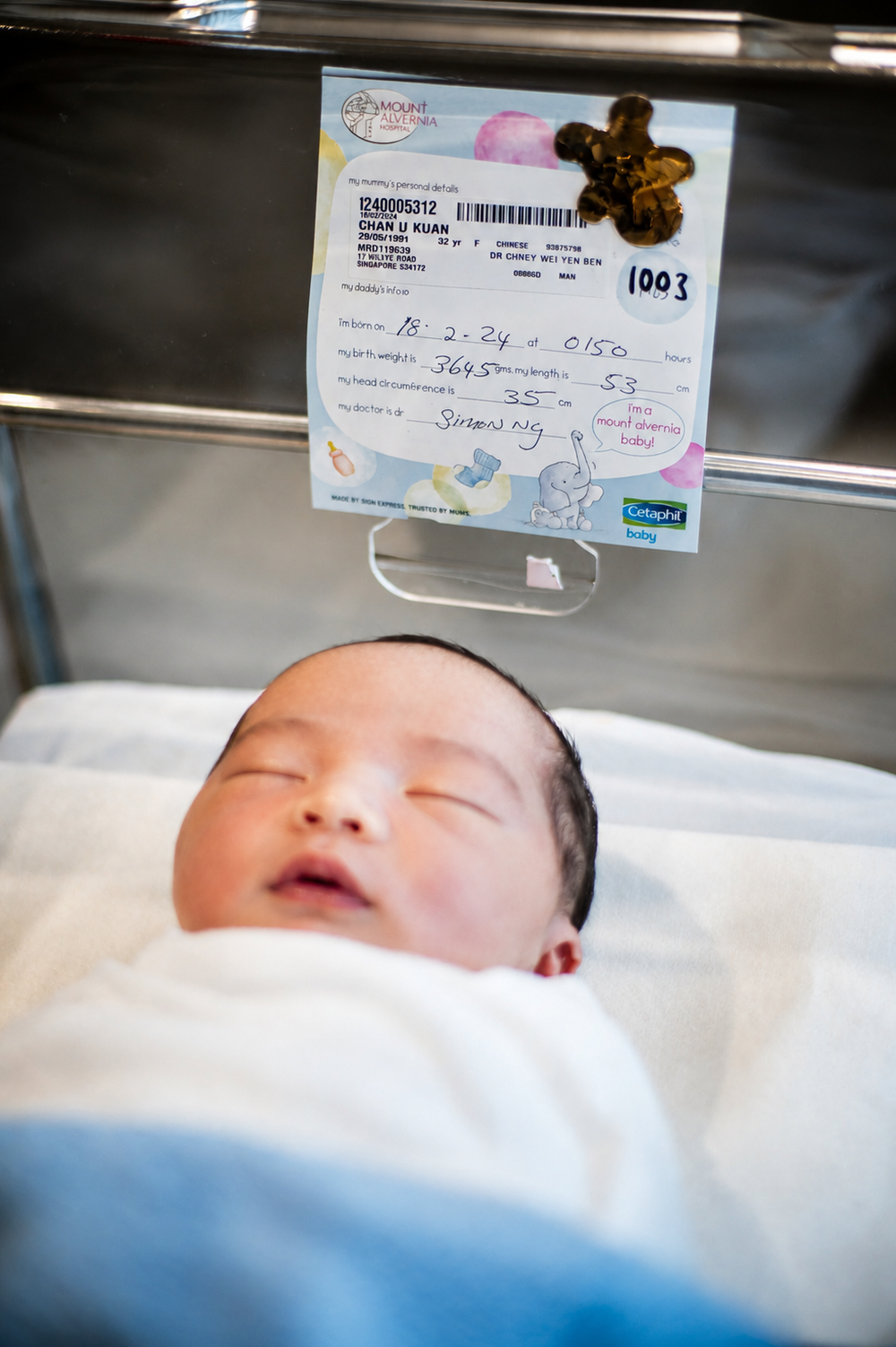 Sleeping newborn baby in hospital bassinet with identification card.