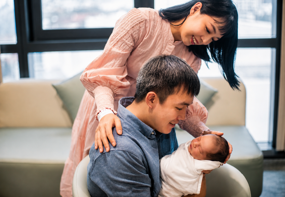 Asian couple sharing a tender moment with their newborn baby.