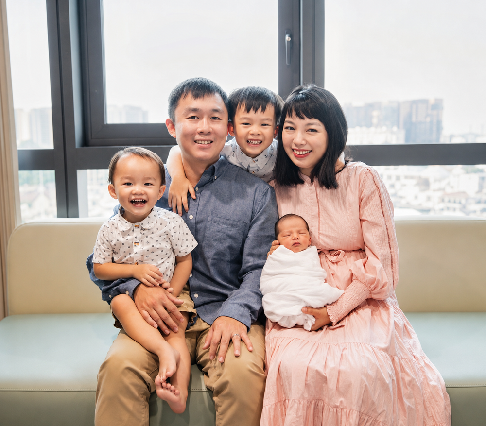 Asian family with two young children and newborn baby smiling together.
