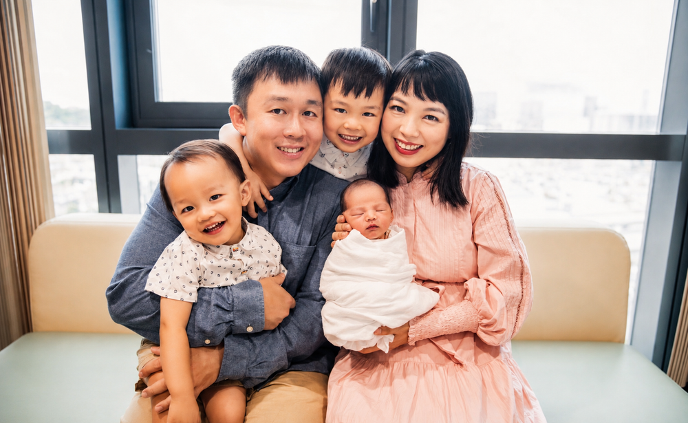 Joyful Asian family portrait with parents, two kids, and newborn baby.