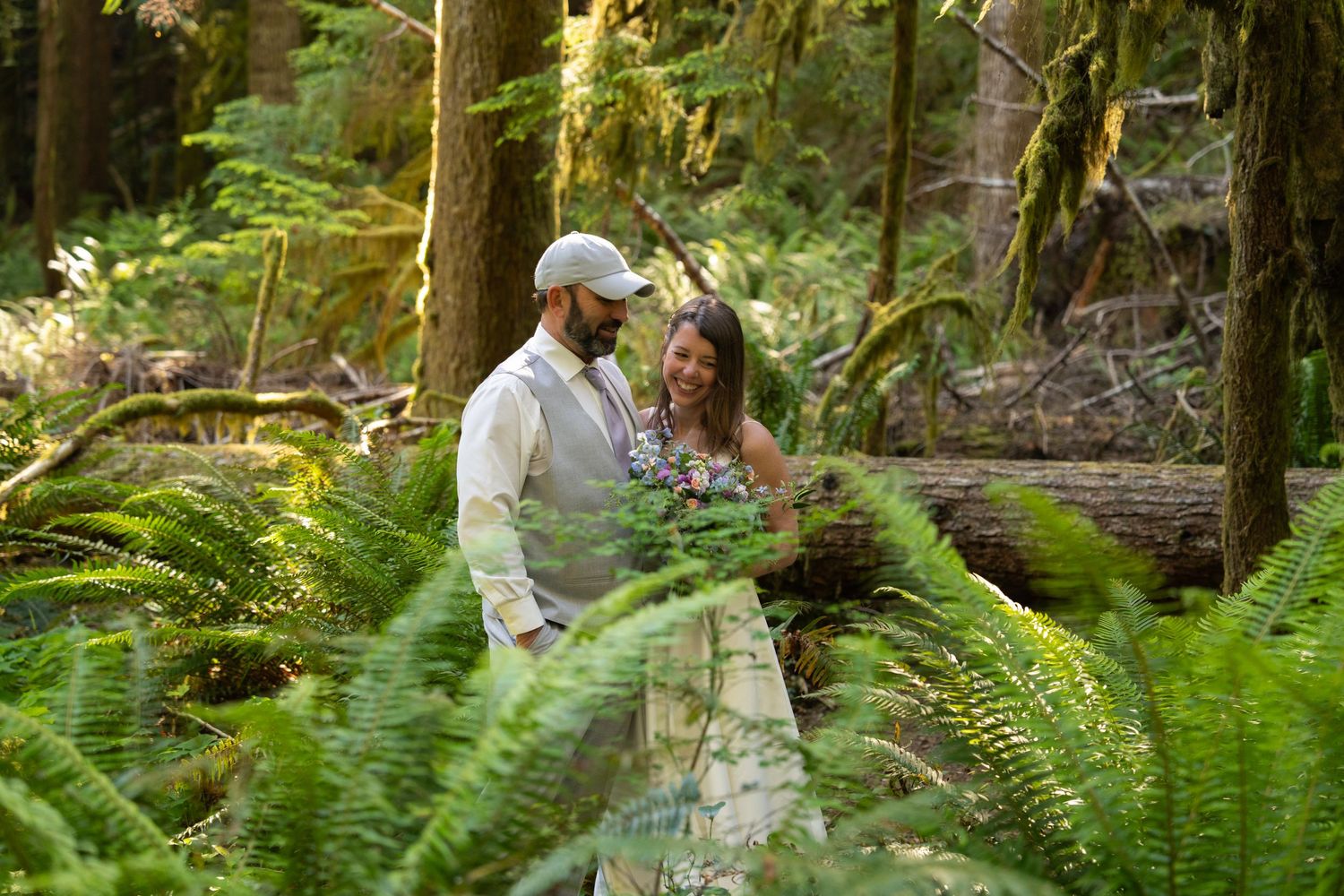 A couple embraces romantically among lush green ferns in Olympic National Park, Captured by Savvy Photography