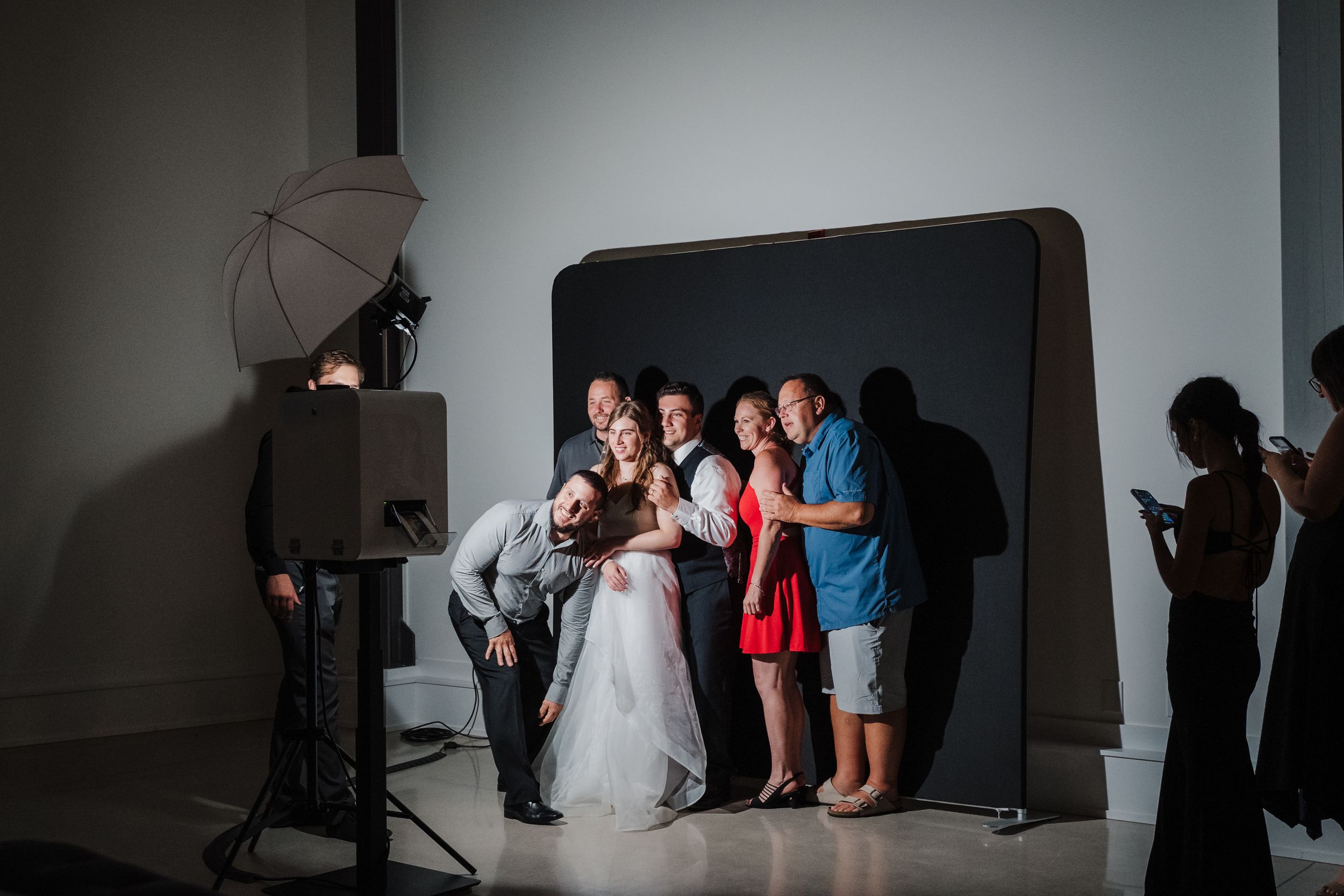 Behind-the-scenes photo shoot setup with lighting equipment and photo backdrop in a studio.