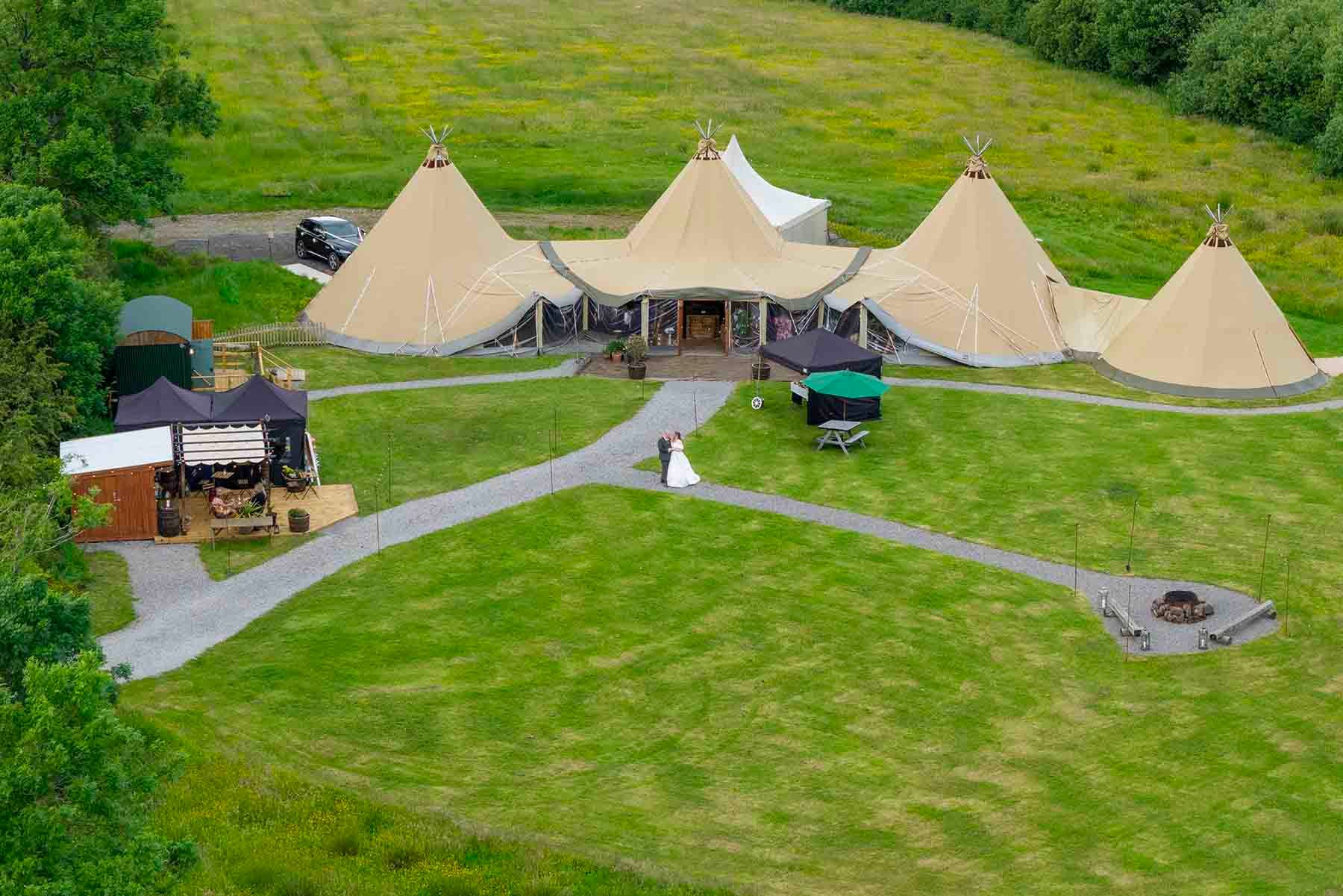 Aerial view of The Den at Four Acre, with linked tipis, lawns and gravel paths surrounding Lucas and Ellie on their wedding day.