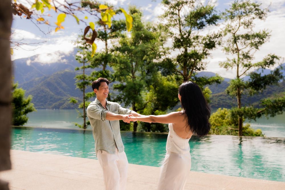 Couple dancing by infinity pool with scenic mountain landscape.