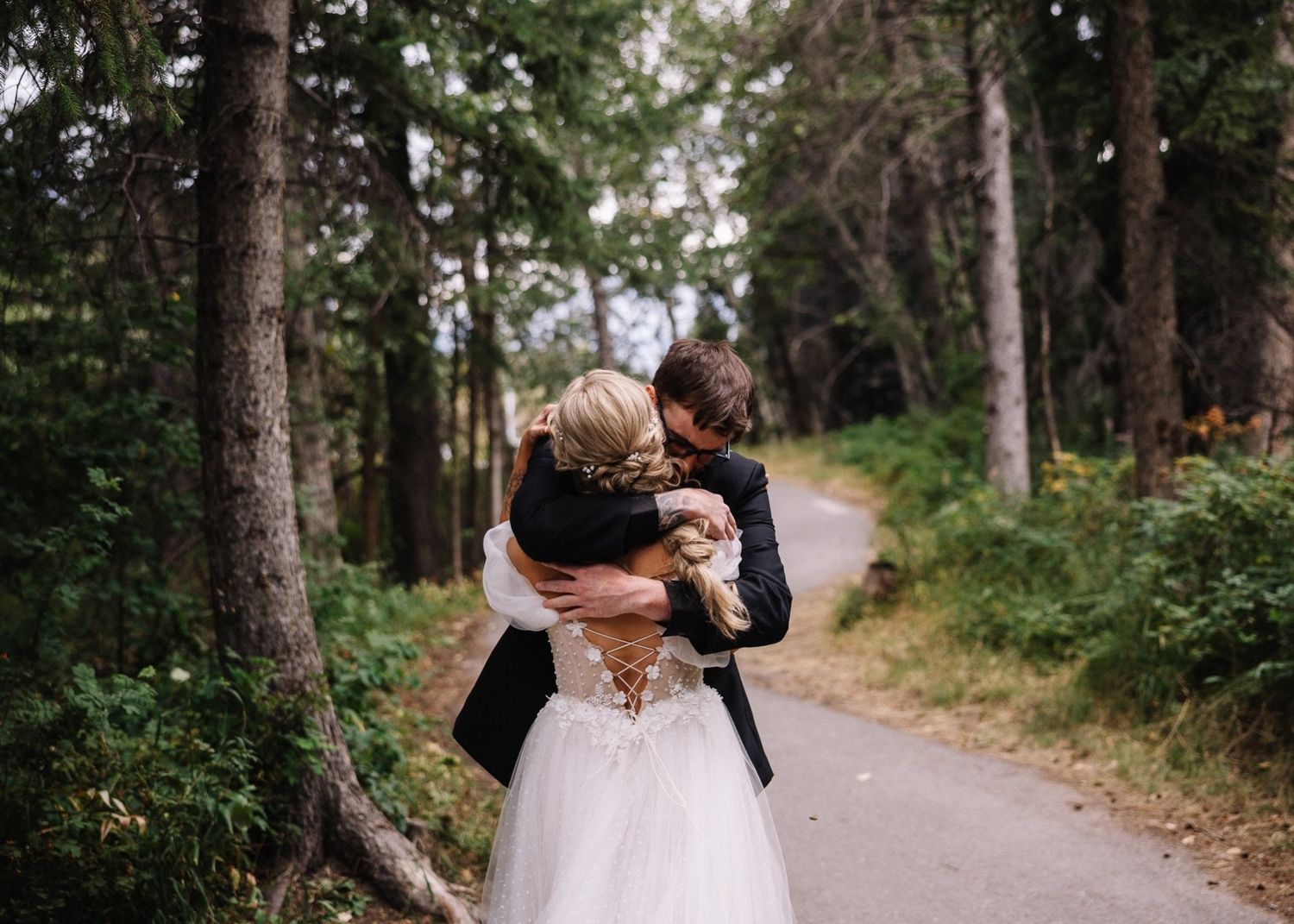 Groom hugging the bride during their forest first look at the Canmore Nordic Centre wedding