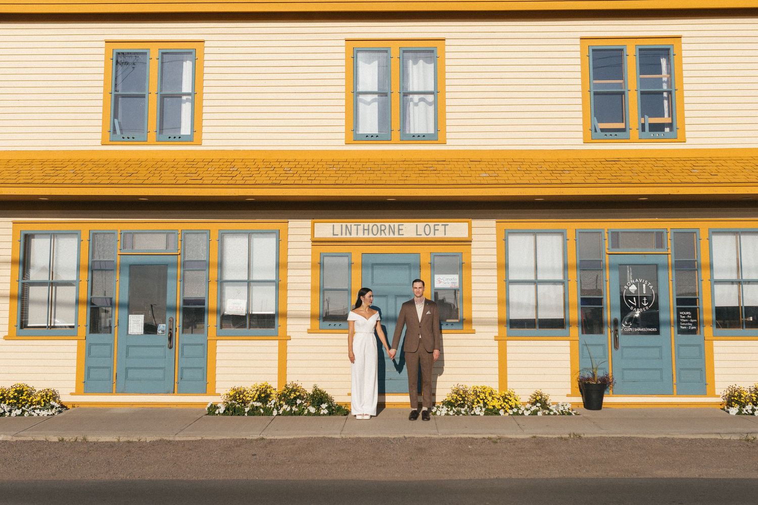 bride and groom hold hands in front of vibrant yellow and blue building