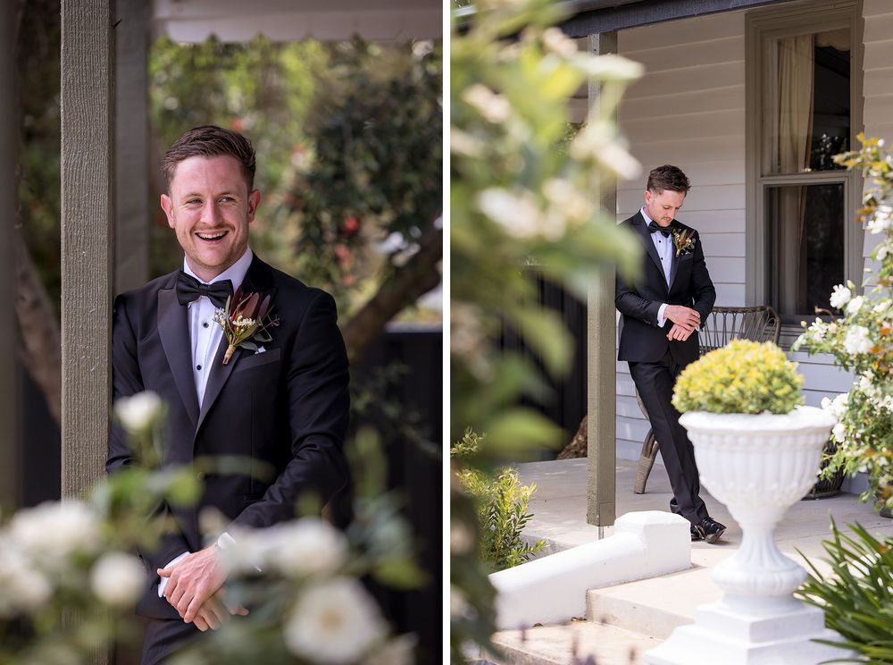 Smiling groom in a black tuxedo and bow tie with a floral boutonniere beside white blooms, then standing on a porch beside a flower urn.