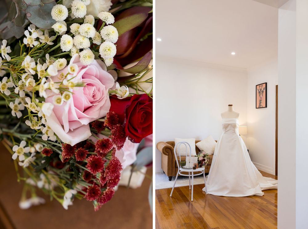 Bridal bouquet of pink roses, red blooms and white flowers beside a white wedding gown displayed in a bright room with a chair.