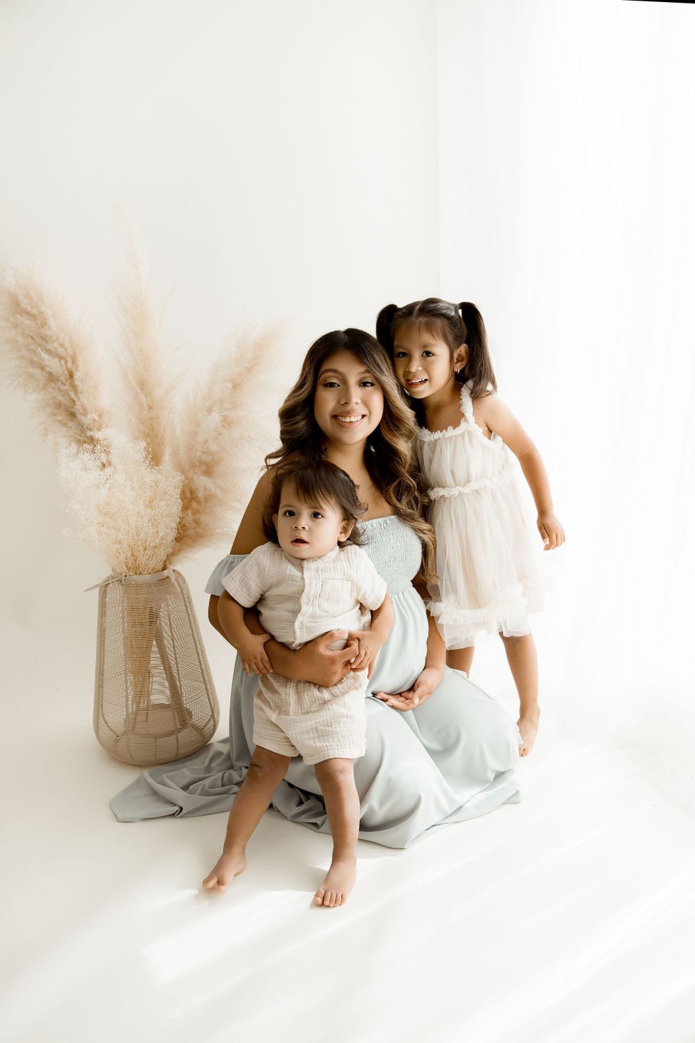 Pregnant mom with two older children sitting on the floor and smiling