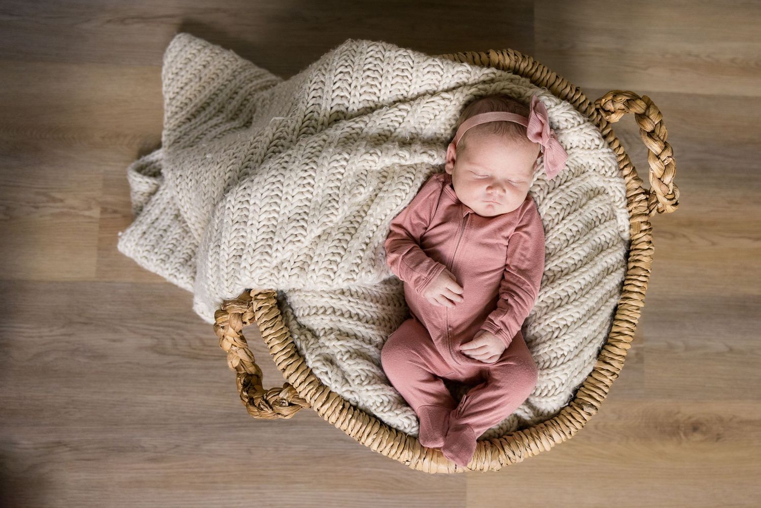 A newborn baby lies in a wicker basket, wrapped in a soft blanket.