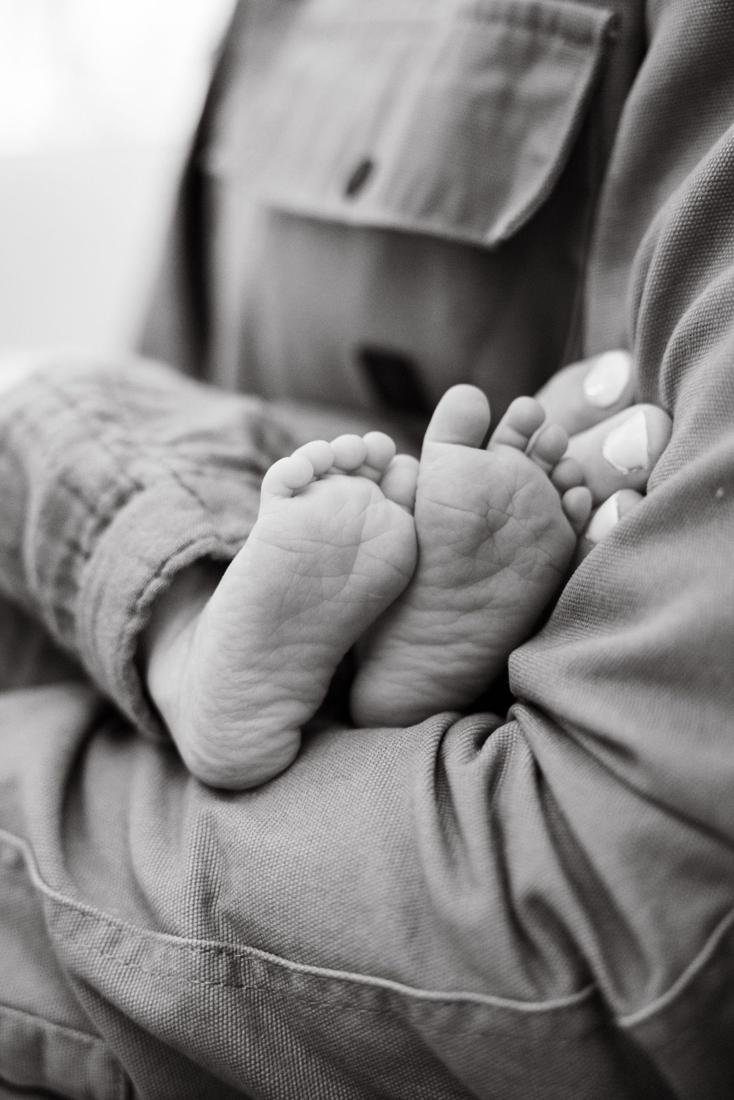 The image shows the feet of a newborn baby wrapped in a soft blanket.