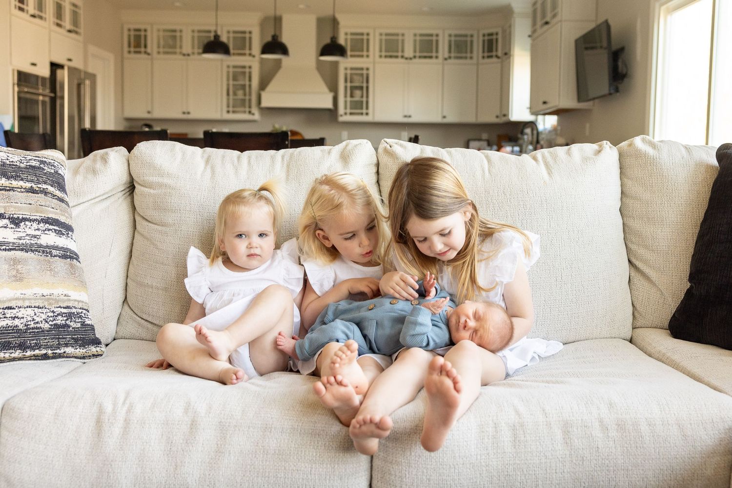 Three young children sitting on a couch in a cozy home environment.