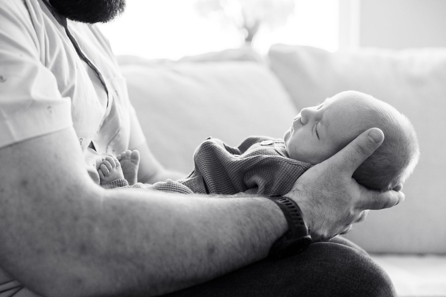 A man holding a newborn baby in his arms, with a tender and protective expression.